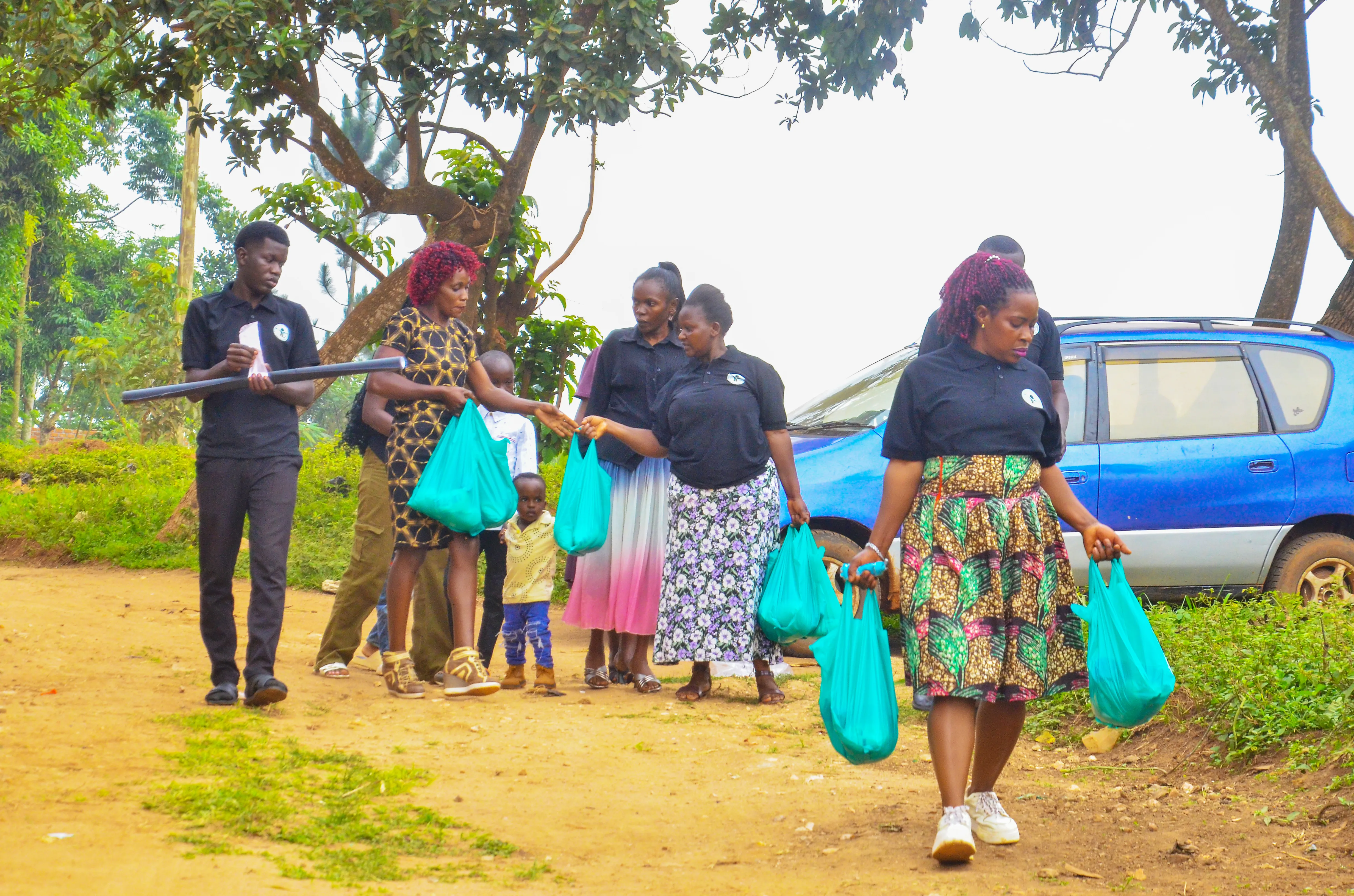 Volunteers walking into a village carrying green food parcels