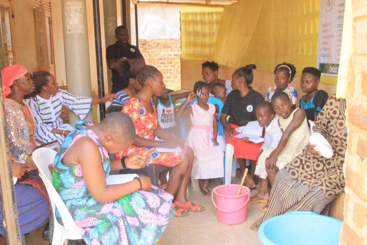 Women and children seated in a training session, taking notes
